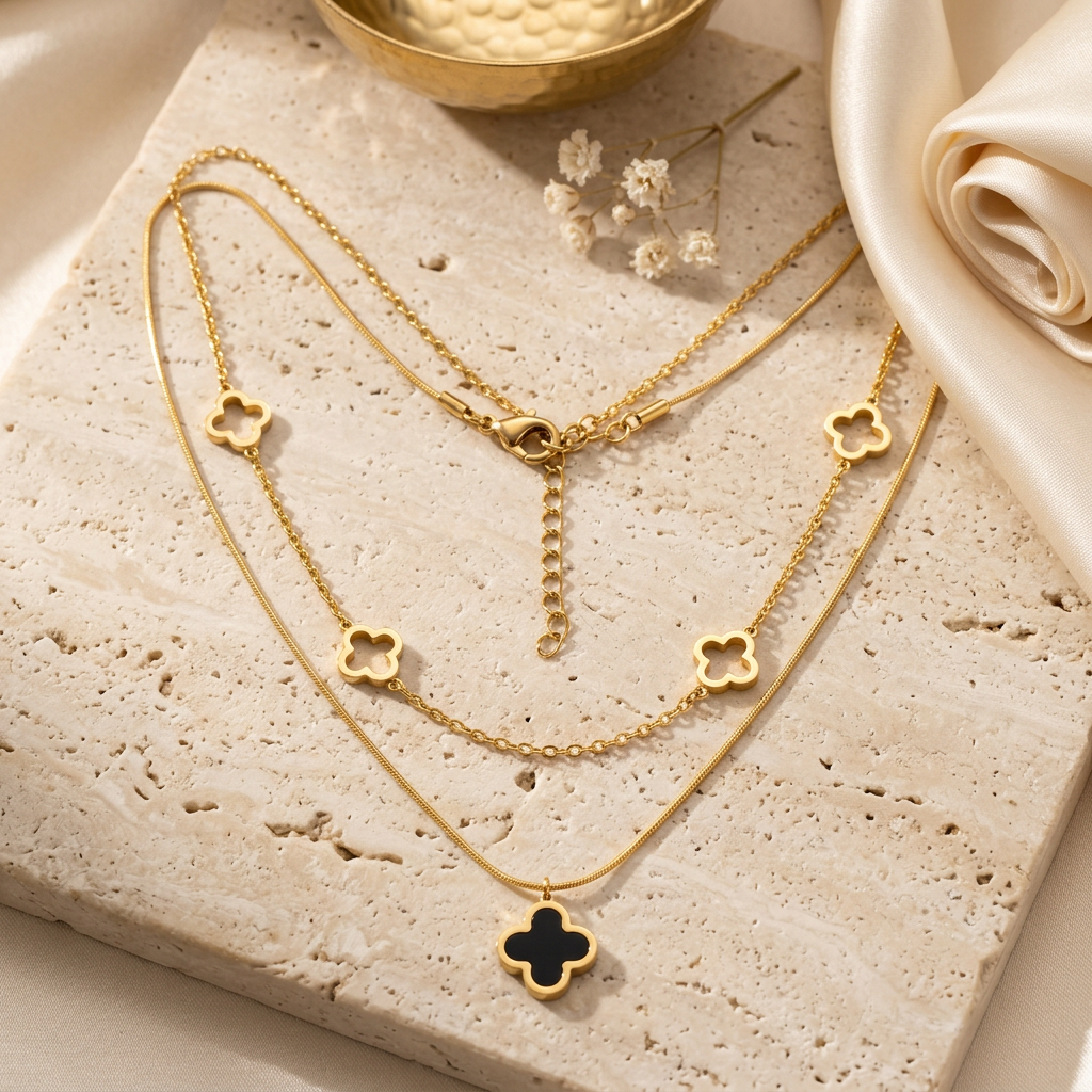 Collier Melissa double chaîne dorée avec pendentif trèfle noir sur fond beige